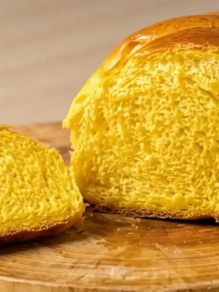 Pão de abóbora caseiro fatiado em tábua de madeira com miolo macio e dourado